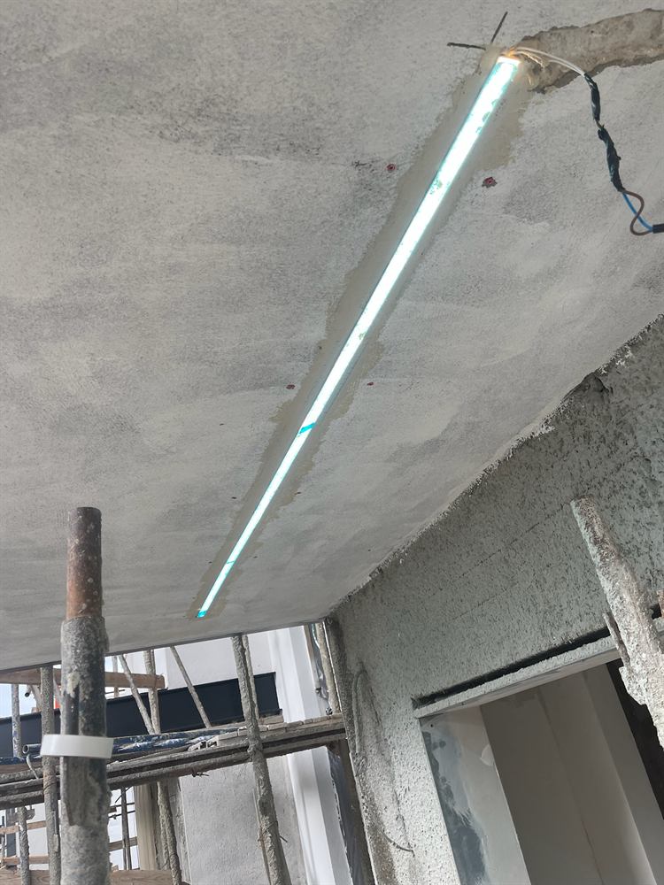 גוף תאורה לינארי מותקן על תקרת בטון באתר בנייה