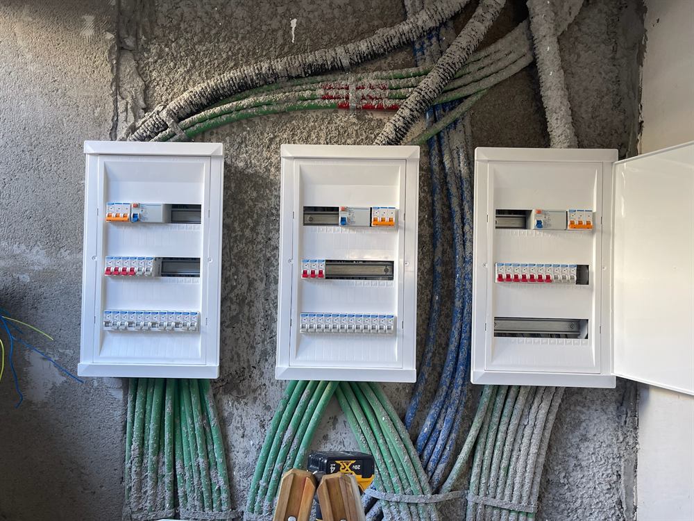 שלושה לוחות חשמל זה לצד זה, עם צנרת מסודרת מתחתיהם
